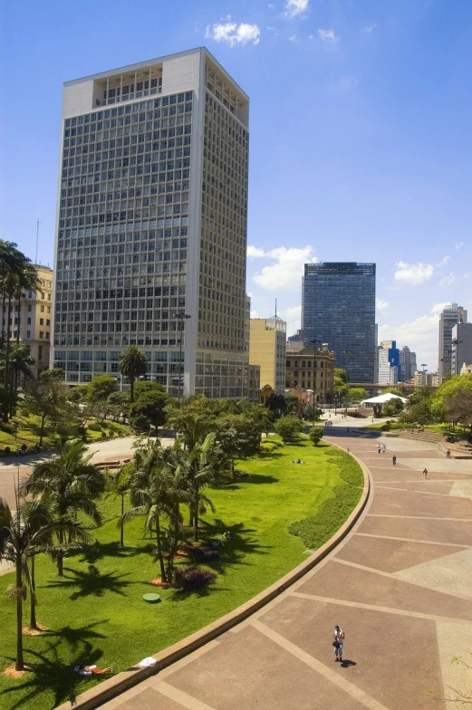 view from the top of a grassy area in front of a tall building with glass windows