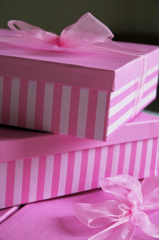 two pink boxes sitting side by side with bows on top