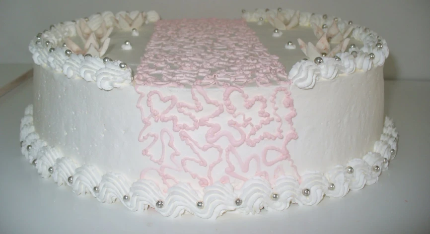 a cake has a white base and pink frosting with some silver details