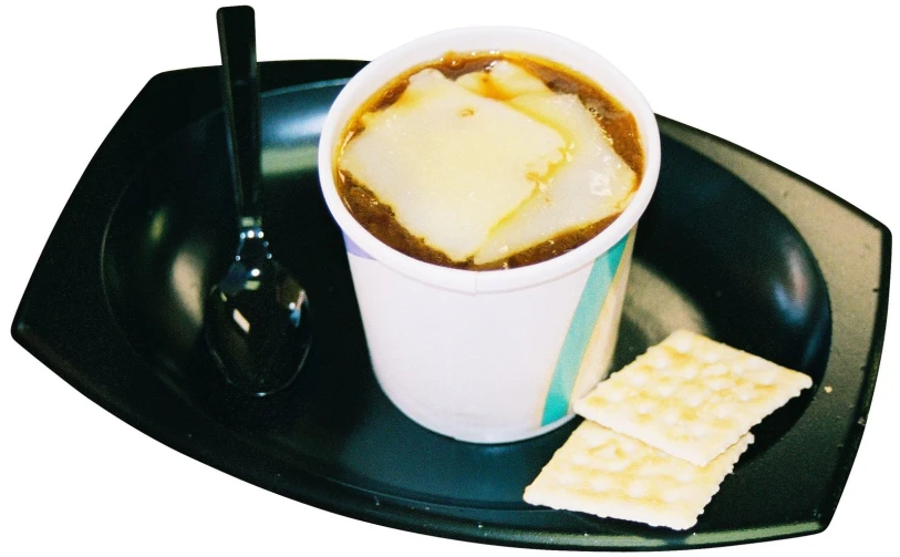 a white cup filled with lots of coffee sitting on top of a black tray