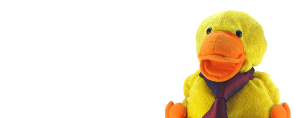 a stuffed duck in a tie sitting down