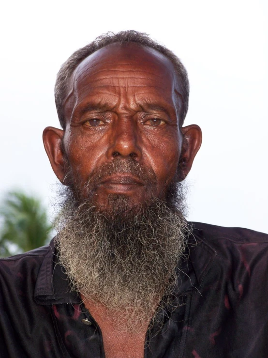 a man with a beard and black shirt is staring in the camera