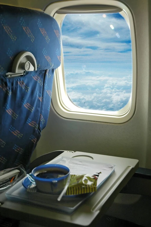 the window in the seat of a plane looking out on the clouds