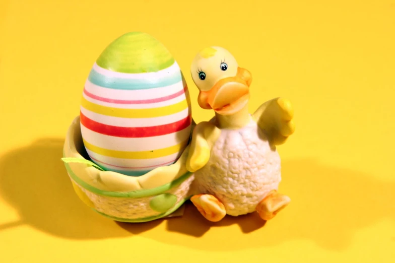 a toy duck sitting in front of an egg