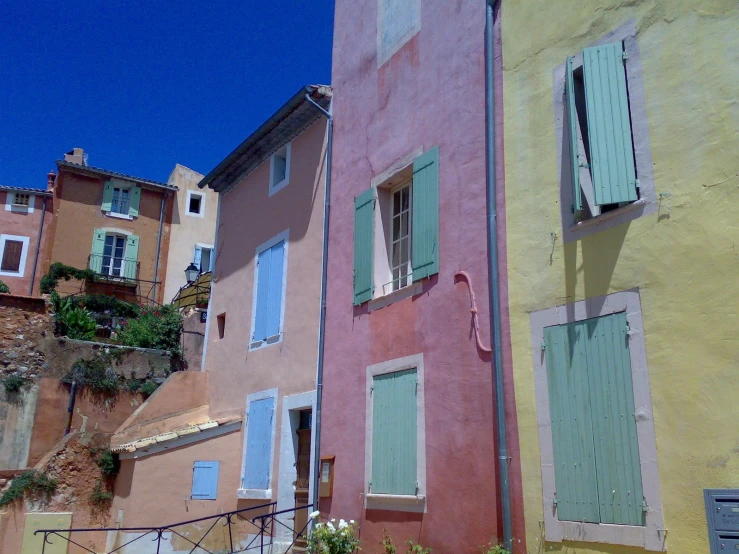 many buildings painted different colors, and each with shutters open