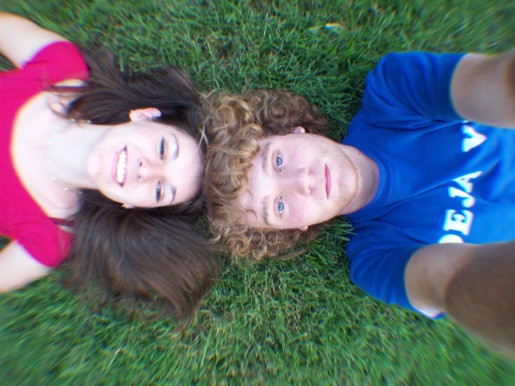two girls laying on top of green grass