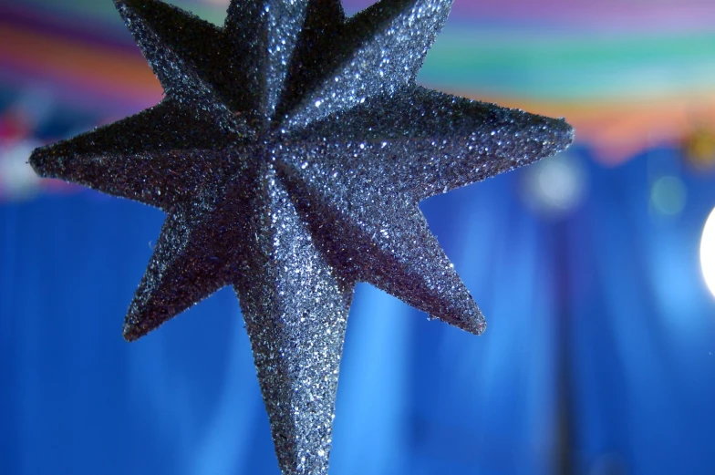 a shiny star hanging in front of a blue curtain