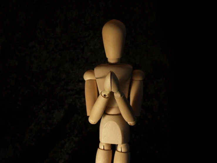 a wooden figure holding another wooden object in the dark