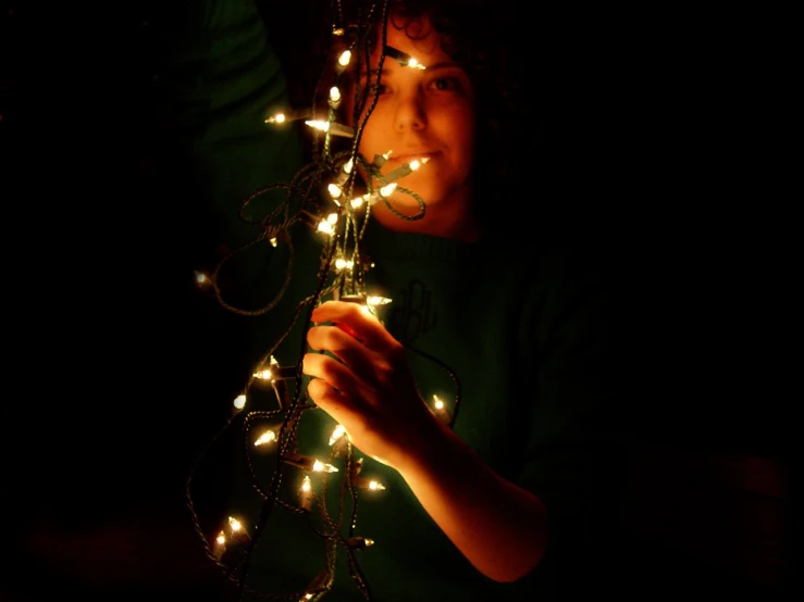  holding christmas lights in the dark