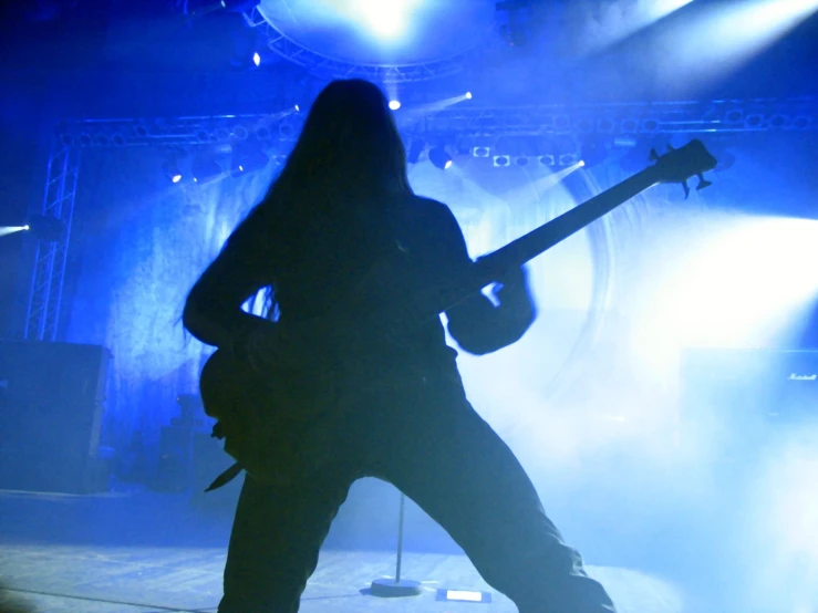 a woman with long hair playing guitar on stage