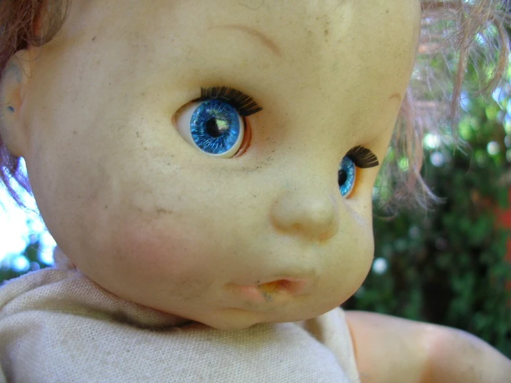 a very close up picture of a doll with big blue eyes