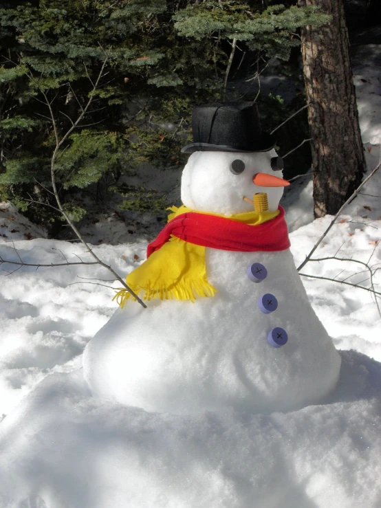 a snowman made to look like it has an orange scarf around its neck