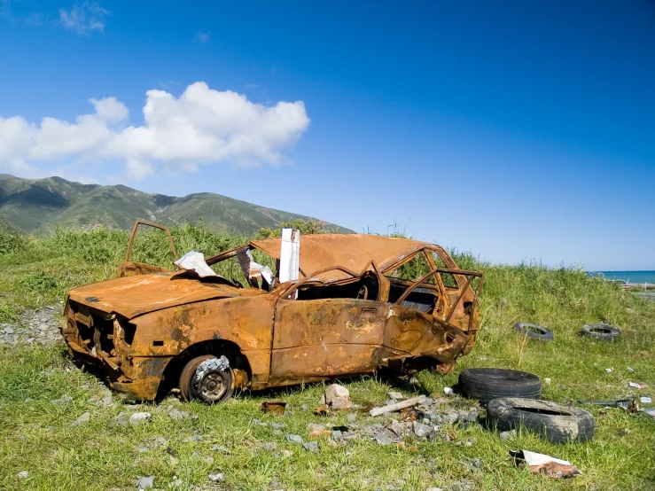 an old car that has been rusted on the side of a road