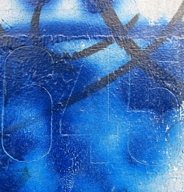 blue graffiti covered wall with a pair of scissors stuck to the side of it