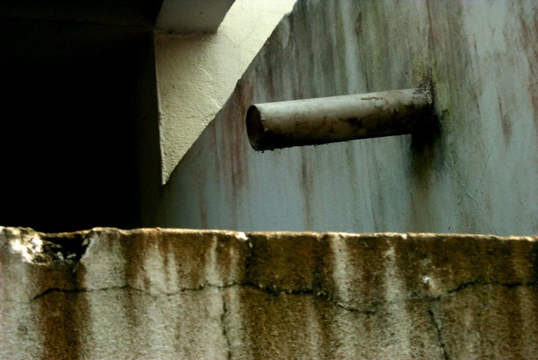 a rusted metal and stone wall with a rusted pole