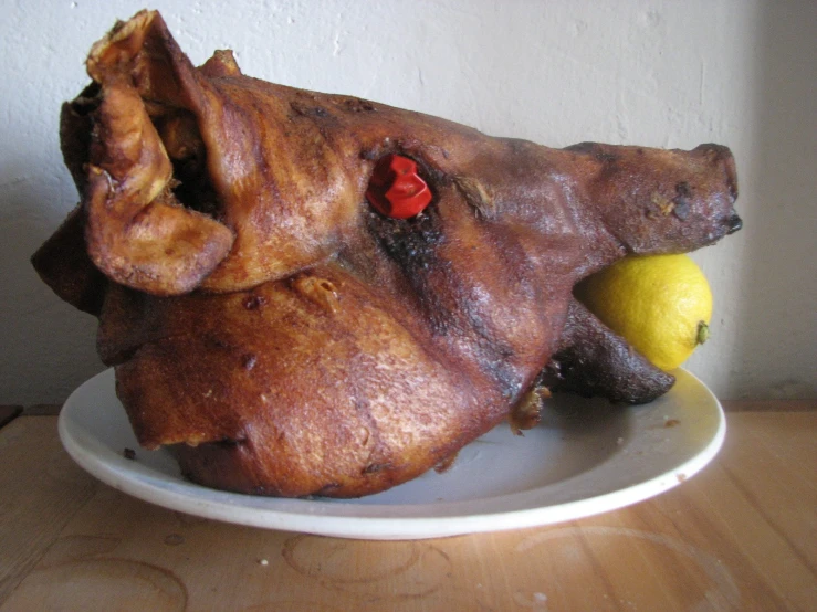 a roast chicken in its belly sitting on a plate next to a lemon