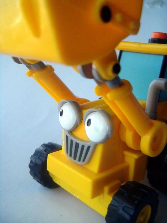 a yellow toy crane holding up two eyes