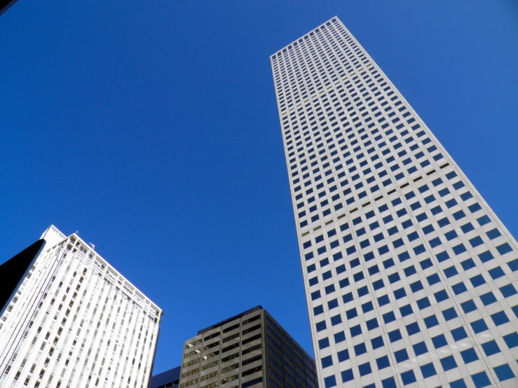 the view of three skyscrs in the city against a blue sky