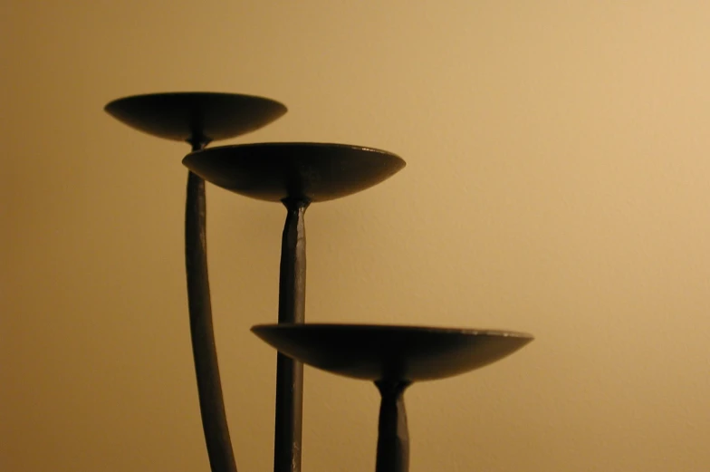 three metal sculptures displayed on beige background