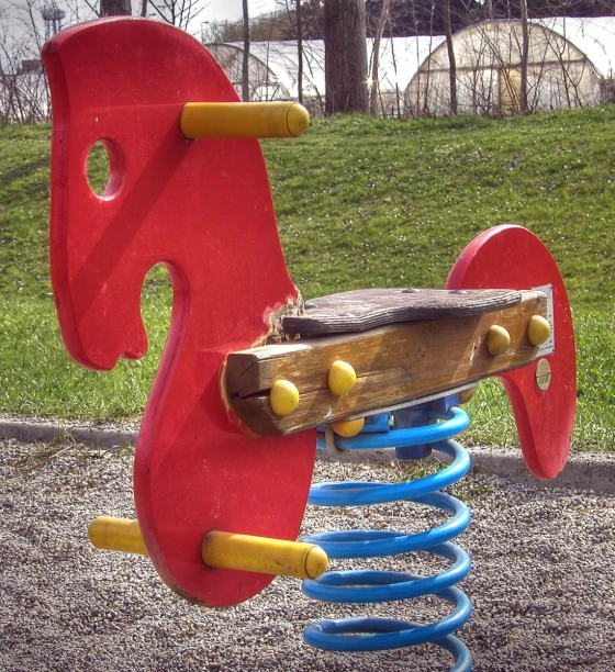 an old red child's slide that has wood and plastic springs
