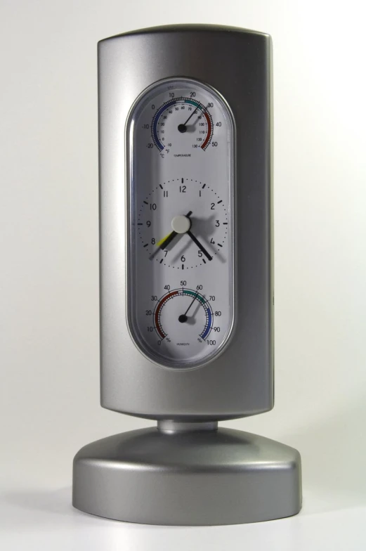 a silver clock is standing on a white surface