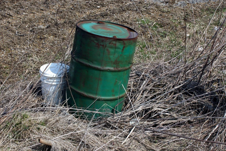 an old barrel and can are among tall grass
