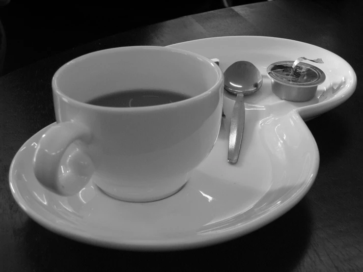 a plate with a spoon and a cup of coffee on it