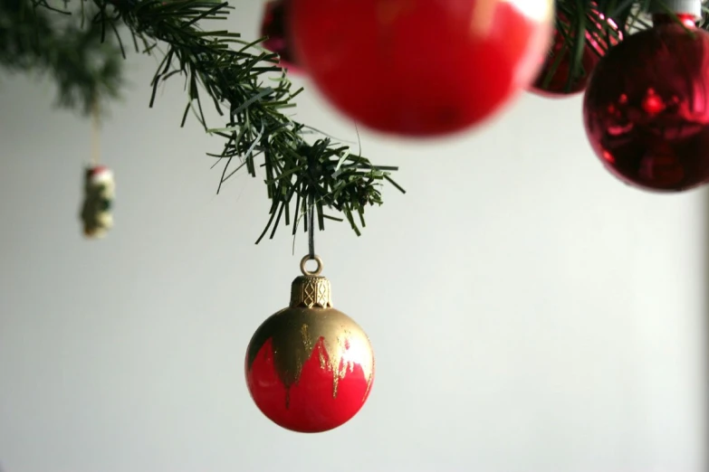 three red and gold christmas balls hanging on a tree nch