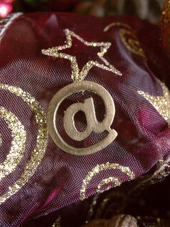 a red and gold pillow with a silver letter inside