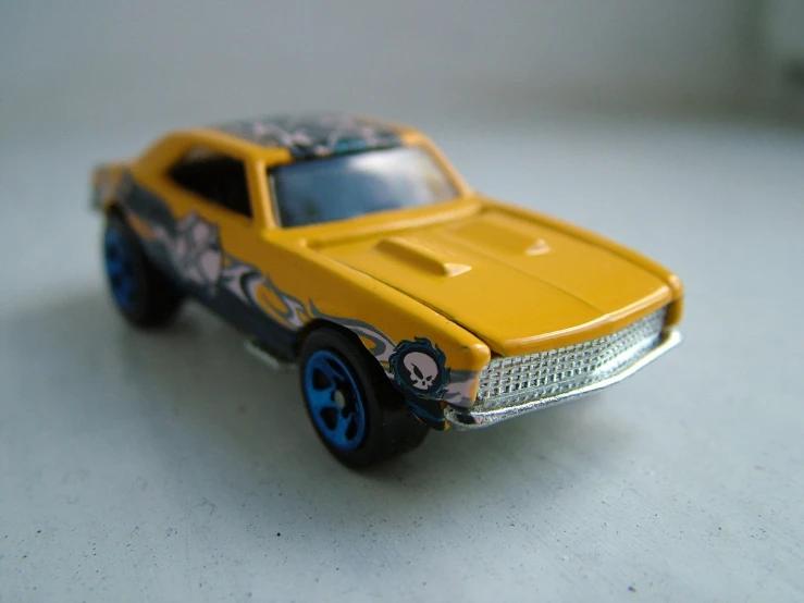 a toy car is yellow and with some black wheels