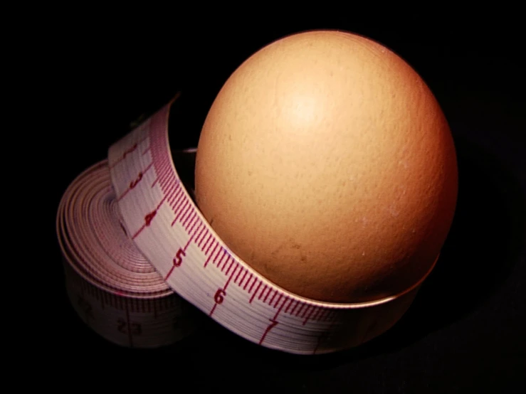 a egg next to some measuring tape