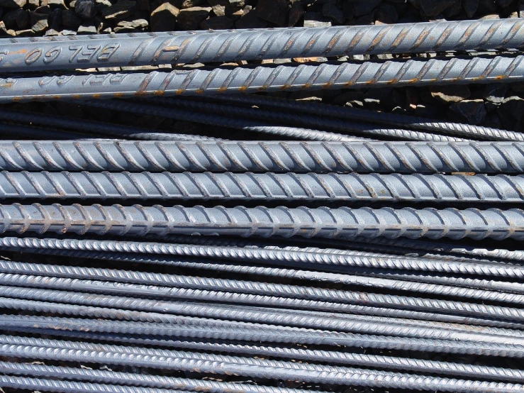 many metal bars are stacked up together in piles