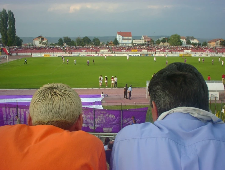 two people watching a soccer match in progress