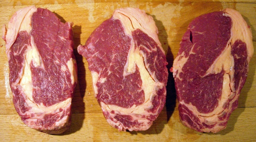 raw steak slices on wooden surface at close range