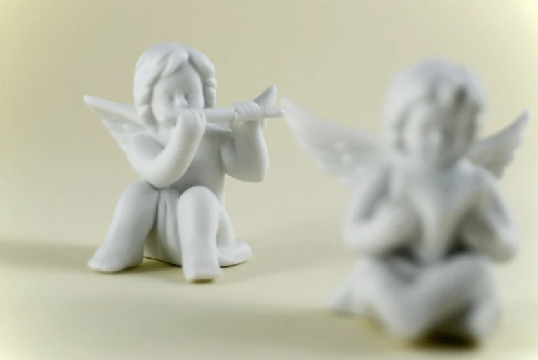 an angel figurine sitting next to another small angel statue