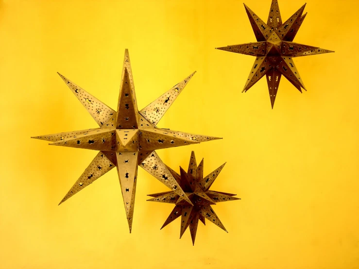 three metal stars on a yellow wall