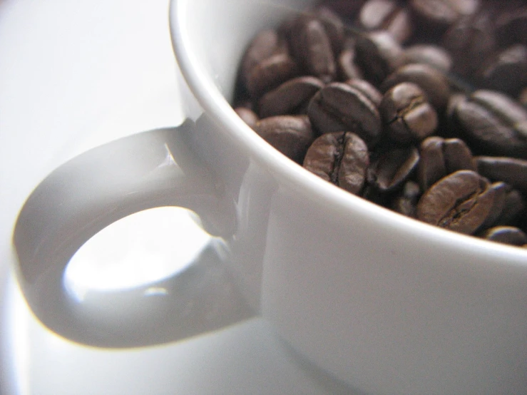 a white coffee cup filled with coffee beans