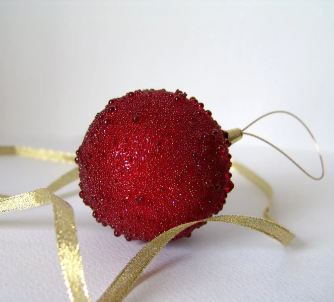 a red ornament with golden ribbon is laying on top of the table