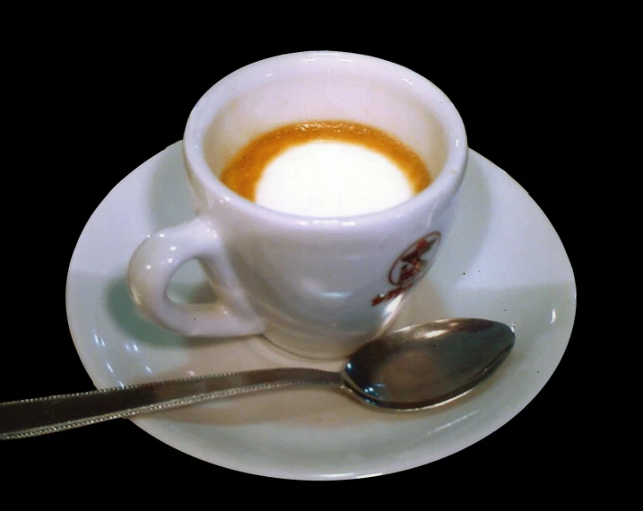 a spoon sits next to a cup on a saucer