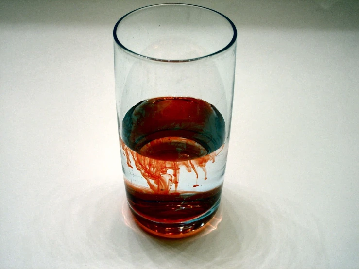 a glass with red liquid and orange substance