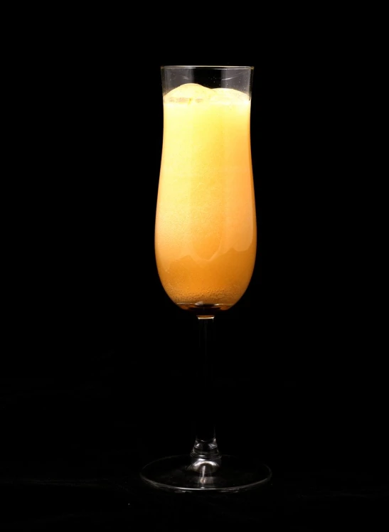 orange juice in a glass, with some on the black table