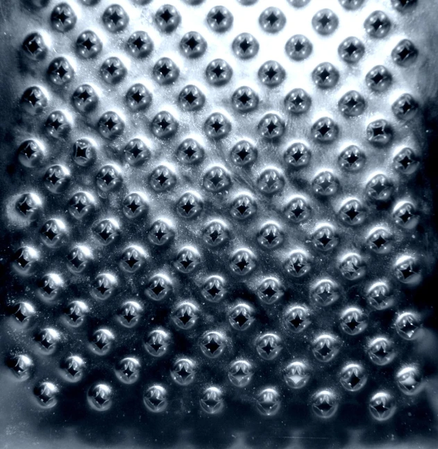 chrome balls sit in a grated pattern on a glass container