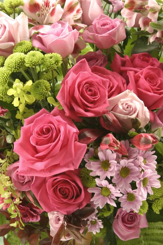 an arrangement of roses and greenery in a vase