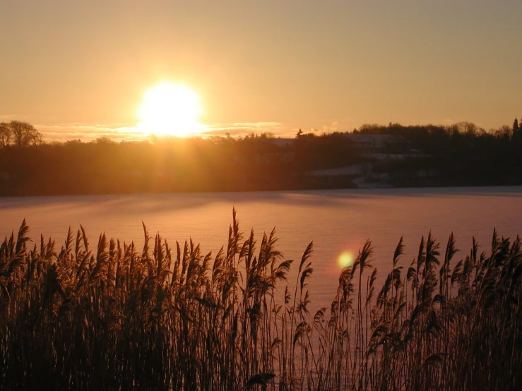 the sun is setting over a frozen lake