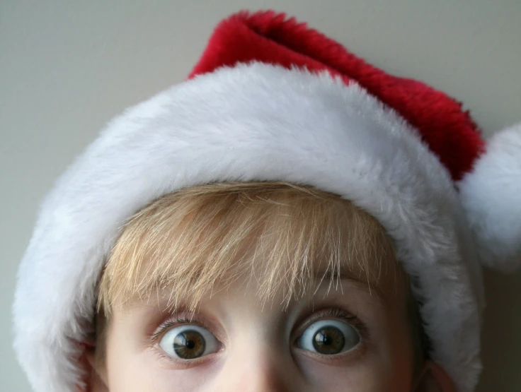 a young child wearing a santa hat and looking up