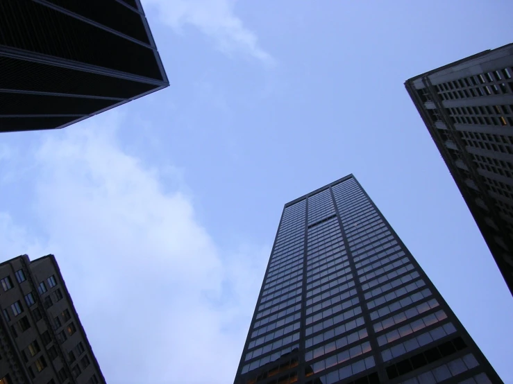 tall buildings stand near each other against a cloudy blue sky