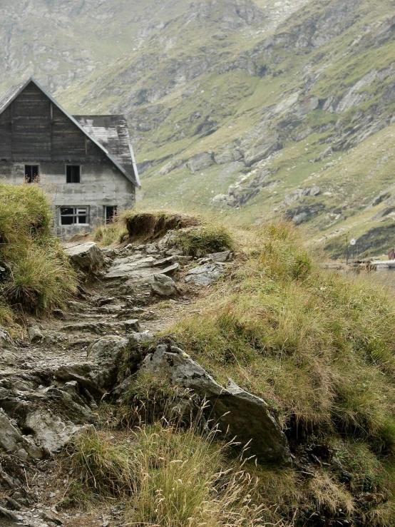an old house stands on a hillside, in the mountains