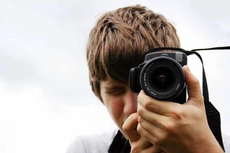 a boy holds up a camera in front of his face