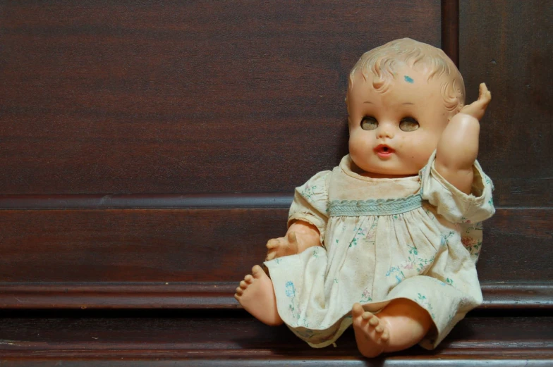 a close up of an infant doll on a wood table