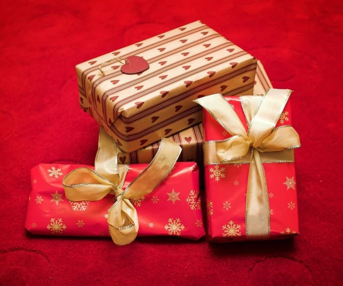 three presents wrapped with ribbons on red ground